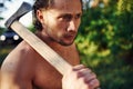 Confident look. Close up portrait of woodsman with axe in hand. Handsome shirtless man with muscular body type is in the Royalty Free Stock Photo
