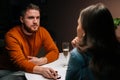 Confident loving young man making proposal for marriage to unrecognizable pretty woman sitting at table with candles Royalty Free Stock Photo