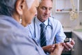 Confident male doctor examining senior woman with glucometer