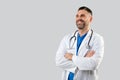 Confident male doctor in uniform posing with folded arms over grey studio background, looking at free space Royalty Free Stock Photo
