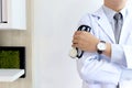 Confident male doctor in white workwear lab coat holding stethoscope standing with arms crossed in corridor of medical clinic, Royalty Free Stock Photo