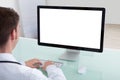 Confident male doctor working on computer at desk