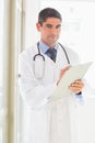 Confident male doctor writing on clipboard