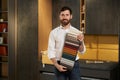 Confident male expert presenting variety samples of upholstery fabric in dark lightened showroom.