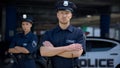 Confident male and female police officers in uniform standing near patrol car Royalty Free Stock Photo