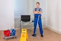 Confident male janitor with cleaning equipments