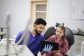 Confident male smiling professional dentist showing tablet pc computer to happy kid patient Royalty Free Stock Photo