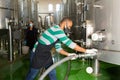 Confident male winegrower working in cellar, filtering wine in barrels