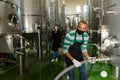 Confident male winegrower working in cellar, filtering wine in barrels