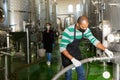 Confident male winegrower working in cellar, filtering wine in barrels