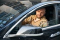 Confident man with beard driving black car.