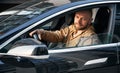 Confident man with beard driving black car.