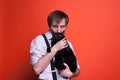 Man holding and kissing black cat and looking at camera on orange background