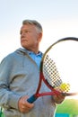 Confident man holding tennis ball and racket on court against clear sky Royalty Free Stock Photo