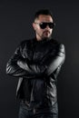 Confident man stand with arms folded. Bearded man in trendy sunglasses. Fashion model in leather jacket and jeans Royalty Free Stock Photo