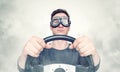 Confident man in stylish goggles with steering wheel, smoke around. Front view. Car driver concept Royalty Free Stock Photo