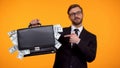 Confident man in suit pointing on briefcase full of dollars, crowdfunding income Royalty Free Stock Photo