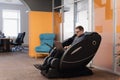 Man writing code while sitting in armchair in the office