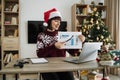 Confident mature adult businesswoman in Santa hat pointing at graphic materials