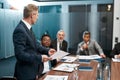 Confident mature businessman in formal wear holding some documet and discussing something with multicultural team while Royalty Free Stock Photo