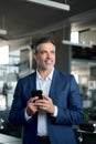 Confident mature businessman leader wearing suit using phone in office. Royalty Free Stock Photo