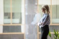 Confident mature businesswoman pondering strategy, standing near window