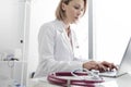 Confident mature doctor using laptop at table in hospital Royalty Free Stock Photo