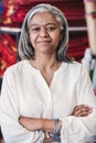 Confident mature fabric shop owner standing among her colorful textiles