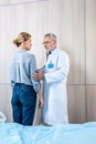 confident mature male doctor examining female patient by stethoscope Royalty Free Stock Photo