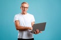 Confident Mature Man Using Laptop in Blue Studio Background Royalty Free Stock Photo