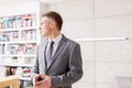 Confident mature salesman looking away while standing against wall in apartment