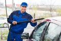 Confident Mature Serviceman Washing Car At Garage