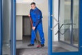 Confident Mature Worker With Broom Cleaning Floor