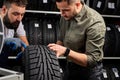 confident mechanic and client checking tires in store Royalty Free Stock Photo