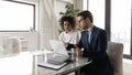 Confident mentor businessman teaching African American businesswoman in office