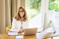 Confident mid aged business woman sitting at desk and using laptop for work