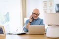 Confident mid aged man using laptop and cellphone while working at home Royalty Free Stock Photo