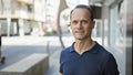 Confident middle age man, in casual fashion, radiates happiness as he enjoys standing in the city street, all under the sunny Royalty Free Stock Photo