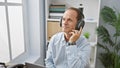 Confident middle age man living it up at work, caught in the rhythm, smiling business worker enjoys his music indoors at the Royalty Free Stock Photo