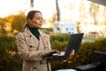 Confident middle aged beautiful woman, freelance, business person working on laptop, standing in the outdoor cafe on at beautiful Royalty Free Stock Photo