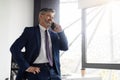 Confident Middle Aged Businessman In Suit Talking On Cellphone In Office Royalty Free Stock Photo