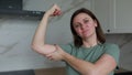 Midlife Woman Demonstrating Muscle Flexing In Modern Kitchen During Daytime