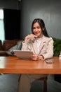Confident millennial Asian businesswoman sits at her desk with her digital tablet Royalty Free Stock Photo
