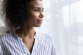 Confident millennial black woman stand by window look forward visualize