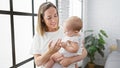 Confident mother standing in a living room, lovingly holding her smiling baby daughter in her arms, sharing a happy moment at home Royalty Free Stock Photo