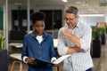 Confident multiracial professionals discussing over file document while standing together at office Royalty Free Stock Photo