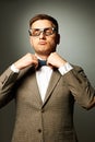Confident nerd in eyeglasses adjusting his bow-tie