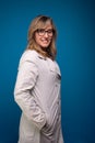 Confident nurse dressed in beige colored coat, wearing eyeglasses with hands in pocket. Confident person Royalty Free Stock Photo