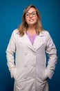 Confident nurse dressed in beige colored coat, wearing eyeglasses with hands in pocket. Confident person Royalty Free Stock Photo