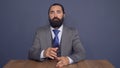 Serious businessman sitting at table in room and straightens tie